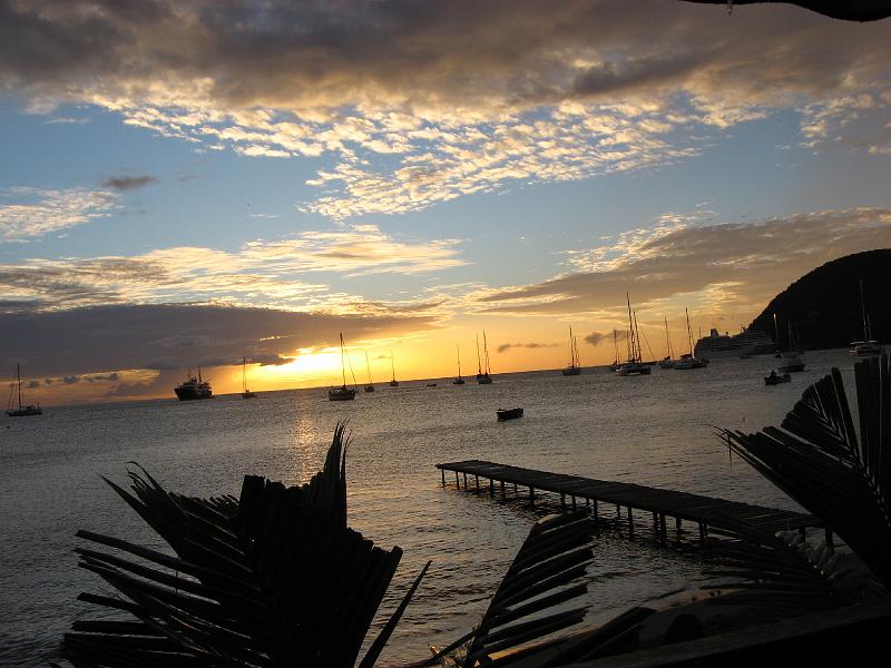 IMG_0892 We enjoyed a dinner starting at sunset with friends Herry & Hildreth at the Blue Bay restaurant, in the Lagon section of Portsmouth on Prince Rupert Bay. The hill on the right is the Cabrits, from which Fort Shirley commands the port.  A cruise ship is docked at the Cabrits. The large ship on the left is a seagoing freighter that has been converted into a private yacht.