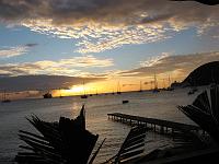 IMG_0892 We enjoyed a dinner starting at sunset with friends Herry & Hildreth at the Blue Bay restaurant, in the Lagon section of Portsmouth on Prince Rupert Bay. The hill on the right is the Cabrits, from which Fort Shirley commands the port.  A cruise ship is docked at the Cabrits. The large ship on the left is a seagoing freighter that has been converted into a private yacht.