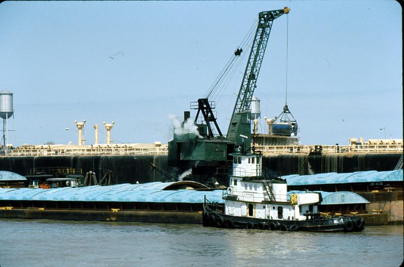 river-10 Loading Mississippi barges.  Note the height of the tug.  The wheelhouse is high so that the tug's pilot can see over the barges as they push them up-river.