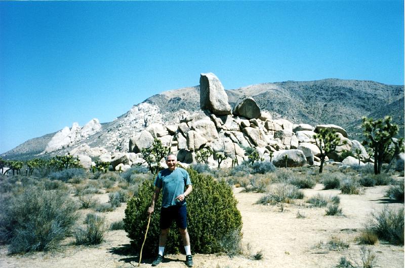06 Look at the rock behind me. The greyish shrubs are called blackbrush. Coleogyne ramosissima .  The shrub behind me is probably another juniper [Juniperus].