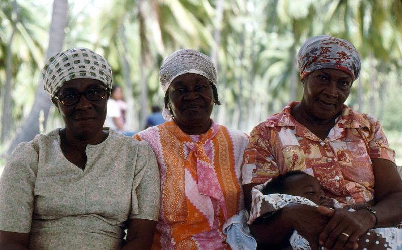 08-three_nice_ladies When we arrived, Ruth foolishly laid in the sun without sunscreen (our luggage had not followed us immediately) and in 10 minutes was seriously burned.  These three kindly ladies took Ruth into their leaf-shade shelter on the beach and soothed her sunburn with aloe that they gathered from neatby plants.